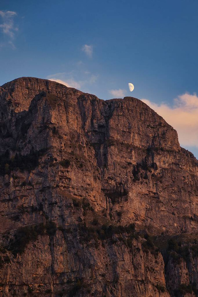 The white tiny half-moon in blue sky over steep rock formation in Zagoria, Greece - Fotó, kép