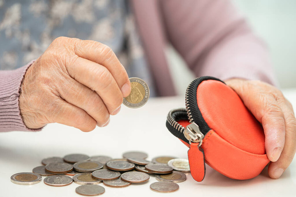 Asijské starší nebo starší stařena drží počítání peněz na mince v kabelce. Chudoba, problém úspor v důchodu. - Fotografie, Obrázek