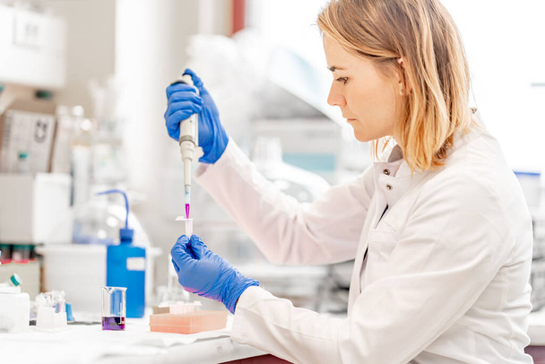 giovane scienziata attraente esamina campioni chimici di sostanze e farmaci in un laboratorio di ricerca. Foto di alta qualità - Foto, immagini
