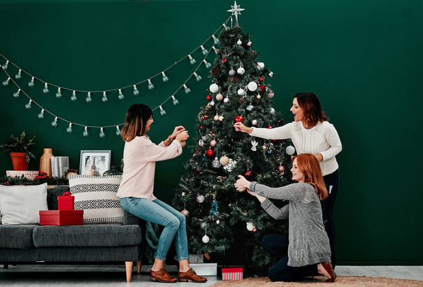 That should go there. three attractive middle aged women decorating a Christmas tree together at home - Valokuva, kuva