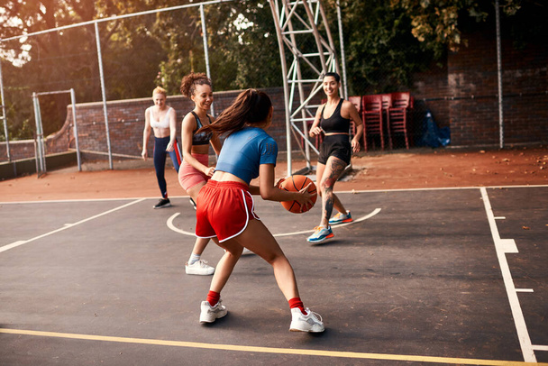 Она заблокирована со всех сторон. разнообразная группа спортсменок, играющих в баскетбол вместе в течение дня - Фото, изображение
