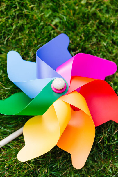 ecology, environment and sustainable energy concept - close up of multicolored pinwheel on green lawn or grass - Valokuva, kuva