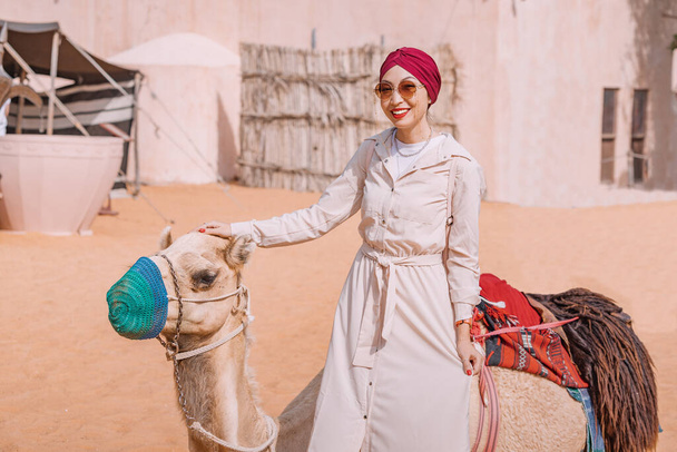 young girl navigates the winding paths of an Arabic heritage village atop her trusted camel companion. Travel adventure concept - Foto, immagini