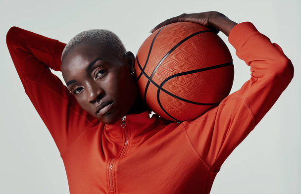 I take my quality time to the court. Studio shot of an attractive young woman playing basketball against a grey background - Fotó, kép