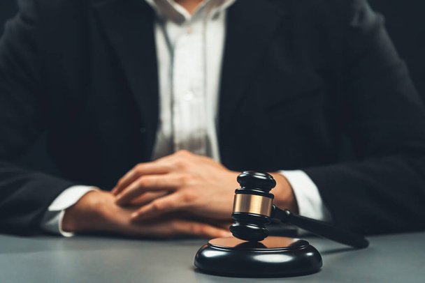 Fókuszban fa kalapács kalapács burkolt hátterű ügyvéd fekete öltöny ül az irodájában asztalán, szimbóluma a jogi igazságosság és integritás, kiegyensúlyozott és etikus döntést a bíróság a jogi egyensúly - Fotó, kép