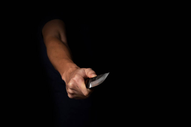 Взрослый мужчина держит острый нож в тени. Концепция картины убийцы, убийцы, убийцы, грабителя или вора. - Фото, изображение