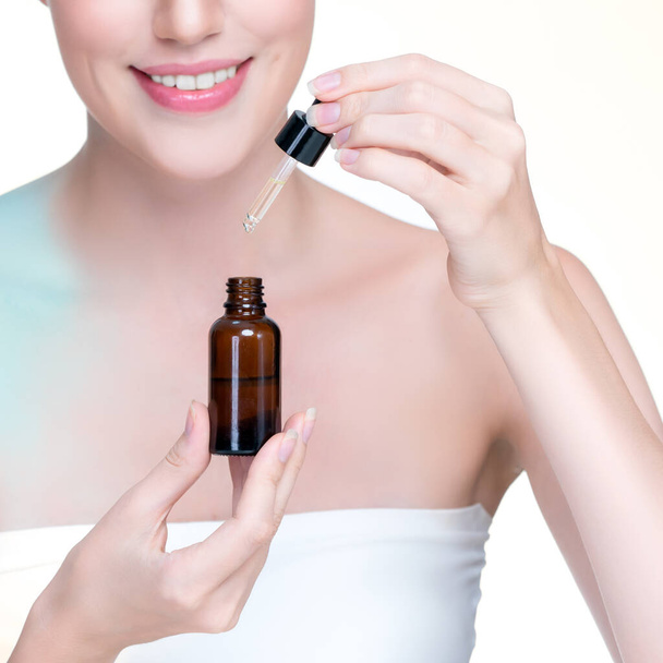 Closeup personable portrait of beautiful woman applying essential oil bottle for skincare product. Cannabis extracted CBD oil dropper for treatment and cannabinoids concept in isolated background. - Foto, imagen