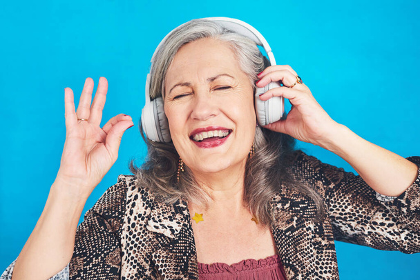 Вот что я называю классическим джемом. фанк и веселая пожилая женщина слушает музыку в наушниках на синем фоне - Фото, изображение