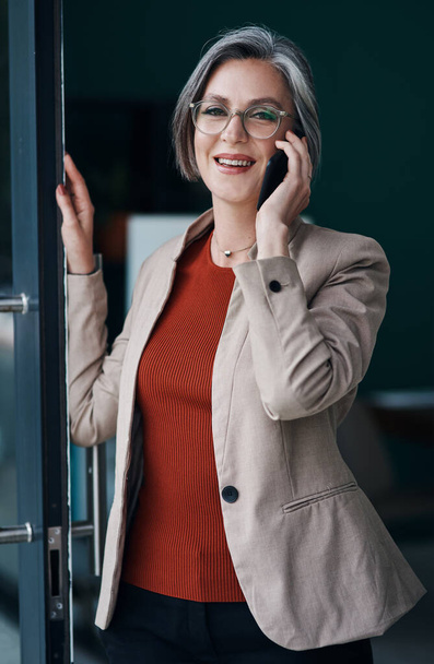Learn to listen to your clients. Cropped portrait of an attractive mature businesswoman standing alone and talking on her cellphone in her home office - 写真・画像