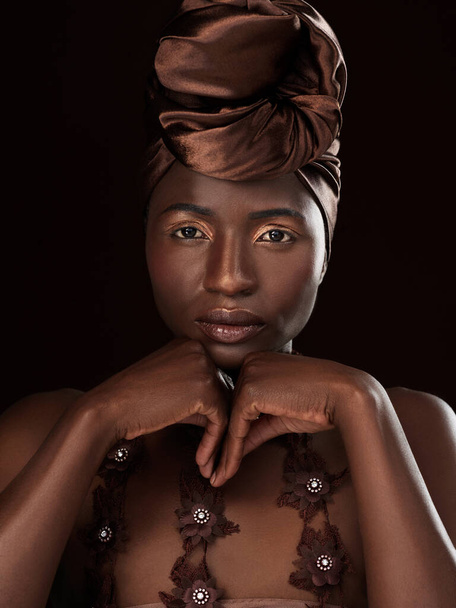 スタイリッシュなヘッドラップのように見えるものは何もありません。黒を背景に伝統的なアフリカの衣装に身を包んだ魅力的な若い女性のスタジオ肖像画 - 写真・画像