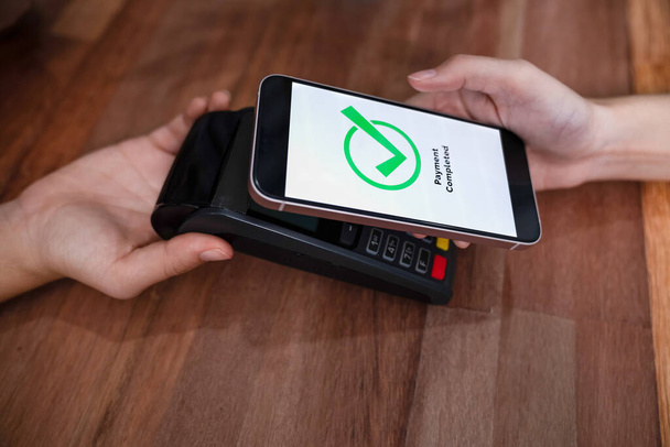 Kod QR jest wyświetlany na ekranie do skanowania płatności bezgotówkowych. Zbliżenie ręce posiadają smartfona do przesyłania pieniędzy drogą elektroniczną transakcji z aplikacji mobilnej. Technologia kodów kreskowych dla szybkiej zapłaty. Entuzjastycznie - Zdjęcie, obraz