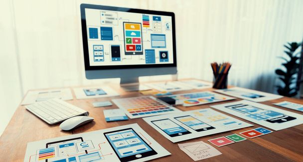 Digitale und papierene Wireframe-Designs für Web- oder mobile App-UI-Displays auf dem Laptop-Computerbildschirm. Panoramaaufnahme des Entwicklerarbeitsplatzes für Brainstorming und Design Application Framework. Prüfen - Foto, Bild