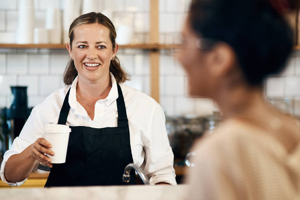 Bu müesseseden. Bir kafede müşteriye bir fincan kahve veren olgun bir barista. - Fotoğraf, Görsel