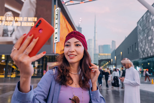 17 Január 2023, Dubai, Egyesült Arab Emírségek: Tourist happy girl taking selfie photos for her travel blog, in Dubai City Walk district against background of the Burj Khalifa - Fotó, kép