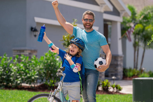 Sporty family. Excited father and son with winning gesture. Father teaching son riding bike. Fatherhood. Support parent. Fathers day. Child care. Fathers day - Zdjęcie, obraz