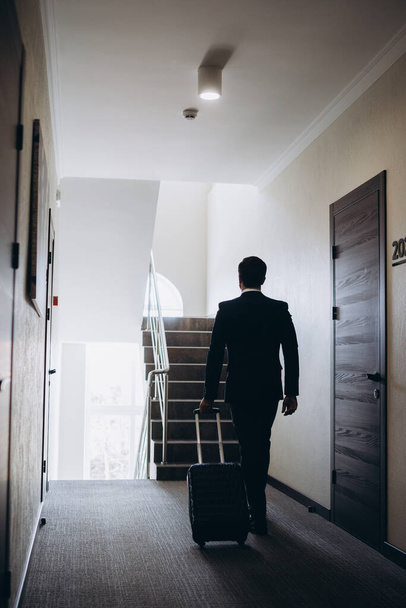Businessman walking with luggage in a hotel corridor - Fotoğraf, Görsel