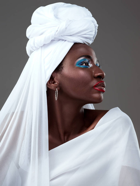 Markayla ilgili değil, tarzıyla ilgili. Gri bir arka planda geleneksel Afrika kıyafetleriyle poz veren çekici bir genç kadının stüdyo fotoğrafı. - Fotoğraf, Görsel