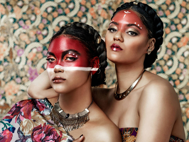 Bőséges szépség található a kultúrában és a hagyományokban. Portré két vonzó fiatal nő öltözött hagyományos öltözék és smink pózol együtt egy mintás háttér - Fotó, kép