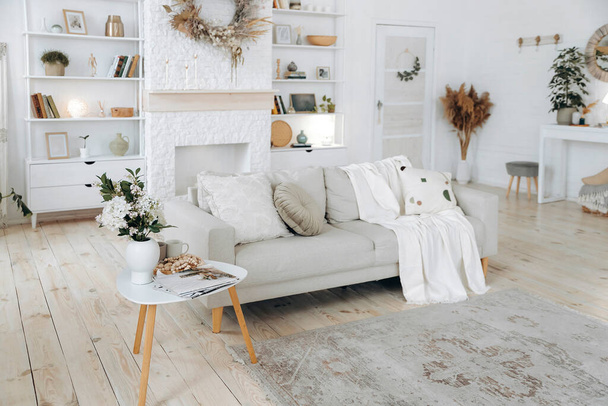 Skandináv stílusú kanapé kockás párnákkal és dohányzóasztallal, modern, világos nappaliban kandallóval, polccal és konzolasztallal. Senki.. - Fotó, kép