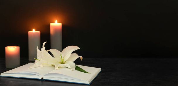 Könyv, fehér liliom virágok és égő gyertyák sötét háttérrel helyet a szöveg - Fotó, kép