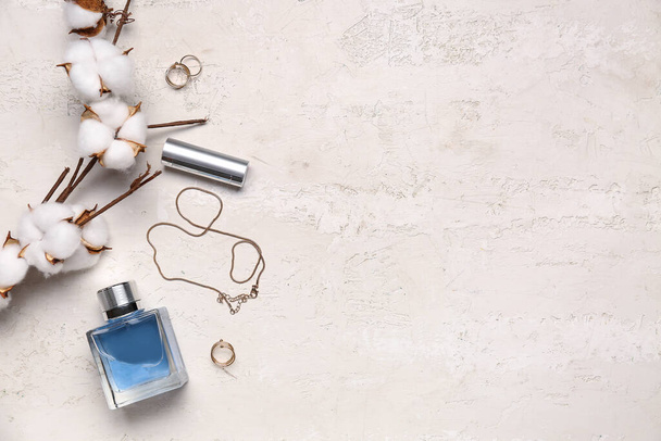 Composición con elegantes accesorios femeninos, botella de perfume, lápiz labial y rama de algodón sobre fondo claro - Foto, imagen