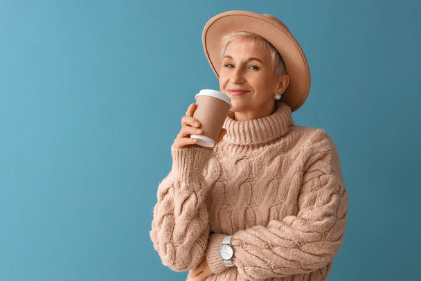 Beautiful mature woman with cup of coffee on blue background - Valokuva, kuva