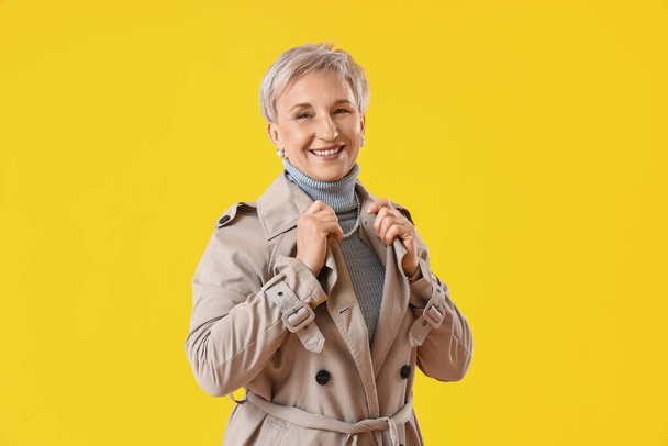 Красива зріла жінка в пальто на жовтому тлі
 - Фото, зображення