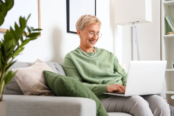 Felnőtt nő használja laptop kanapén otthon - Fotó, kép