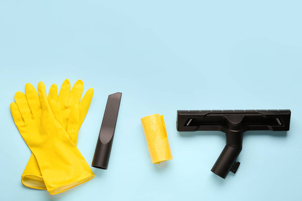 Εξαρτήματα ηλεκτρικής σκούπας με γάντια και σακούλα σκουπιδιών σε μπλε φόντο - Φωτογραφία, εικόνα