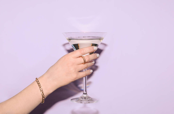Mujer con vaso de martini sobre fondo lila - Foto, Imagen