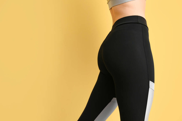 Sporty young woman in leggings on yellow background, closeup - Photo, Image
