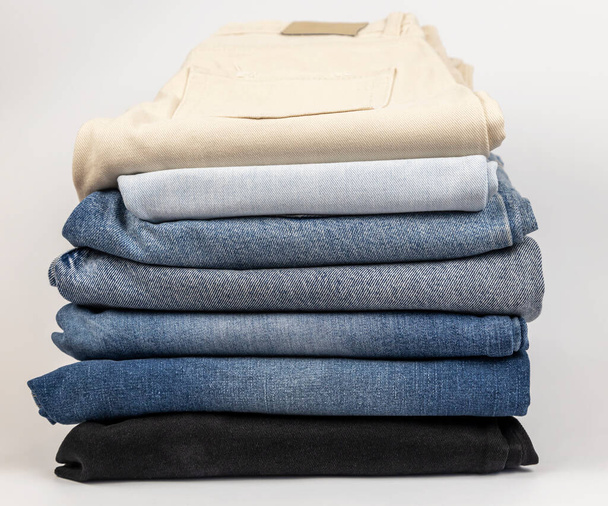 Uma pilha de jeans diferentes, sobre um fundo branco. O conceito de atualização do guarda-roupa - Foto, Imagem