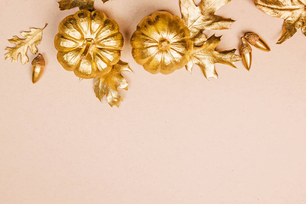 Template with Fall decor in golden colors and empty space. Gold painted leaves, pumpkins and acorns, autumn season composition - Фото, изображение