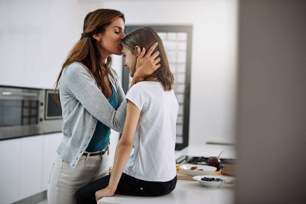 They share a special bond. an attractive young woman kissing her daughter on the forehead while spending time together at home - Fotografie, Obrázek