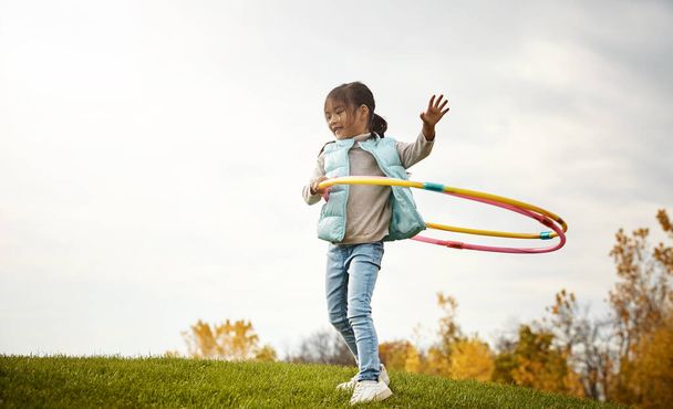 Насолоджуйся веселощами на обручі. чарівна маленька дівчинка проводить день на відкритому повітрі
 - Фото, зображення