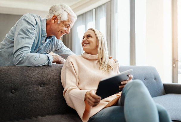 Happy couples share everything. a mature couple using a digital tablet on the sofa at home - Foto, Imagen
