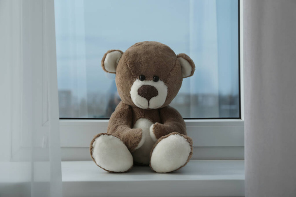 Cute lonely teddy bear on windowsill indoors - Fotoğraf, Görsel