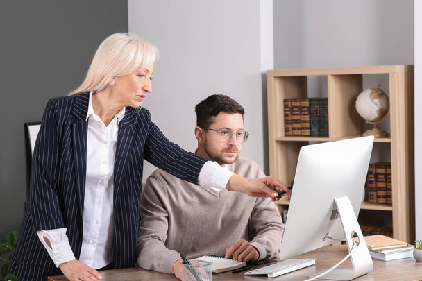 Boss discussing work issues with employee and pointing at computer in office - Foto, Imagen