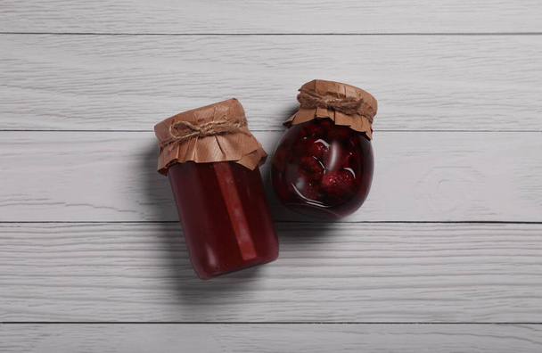 Jars with preserved fruit jams on white wooden table, flat lay - Foto, imagen