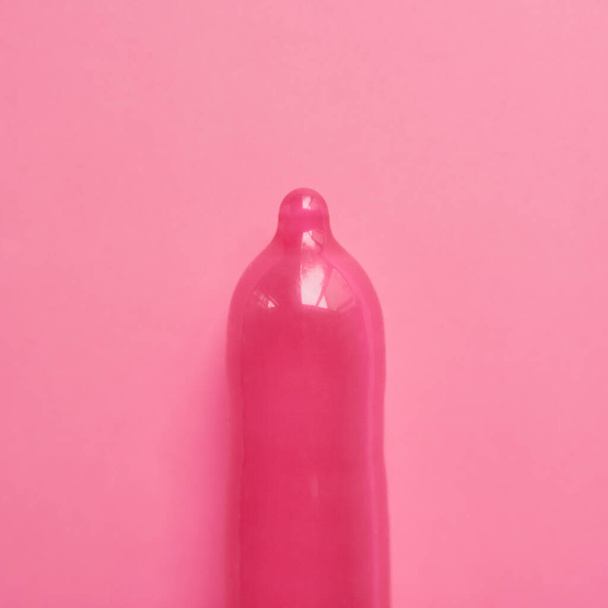 Pink te hace pensar. Estudio plano de un condón rosa colocado sobre un fondo rosa - Foto, Imagen