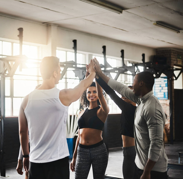 Teamwork makes the fitness dream work. a group of young people giving each other a high five during their workout in a gym - Photo, Image