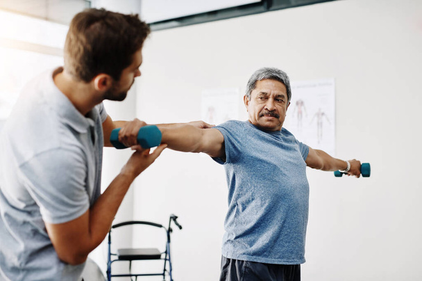 Das ist gut. ein junger männlicher Physiotherapeut hilft einem älteren männlichen Patienten mit Bewegungsübungen in einer Klinik - Foto, Bild