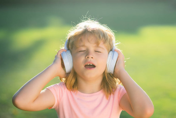 Singing children. Child with listening to music using headphones amazed with open mouth. Funny kids face - Φωτογραφία, εικόνα