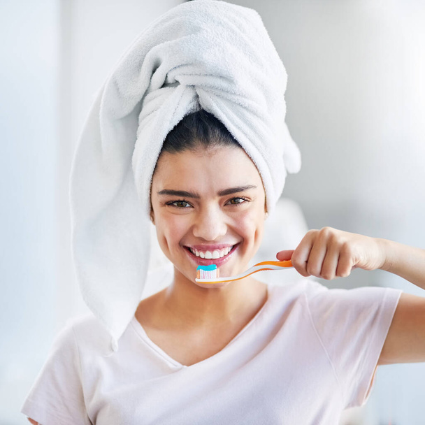 My pearly whites need all the care. Portrait of a beautiful young woman brushing her teeth in the bathroom at home - Photo, Image