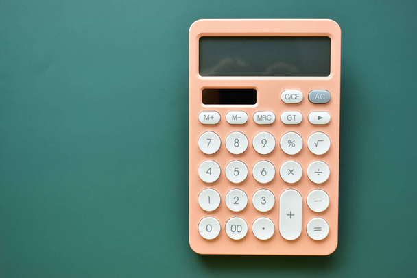 modern peach colour pastel calculator and white button on green background, business and finance accounting concept - 写真・画像