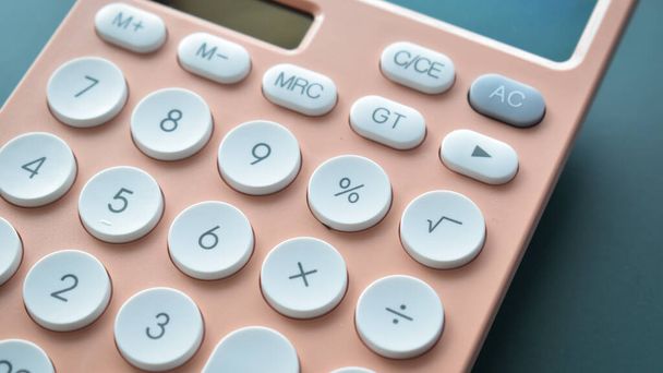 close-up modern perzik kleur pastel calculator en witte knop op blauwe achtergrond, zakelijke en financiële boekhouding concept - Foto, afbeelding