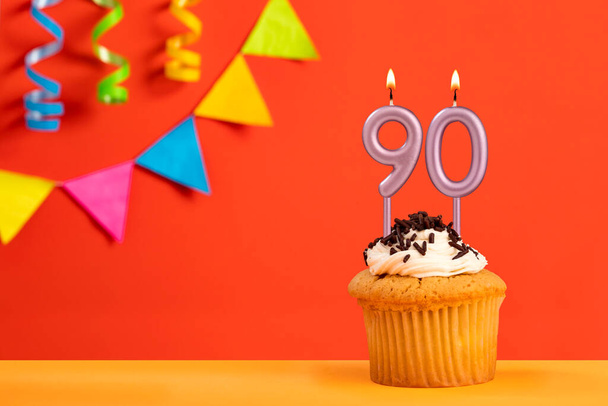 Birthday cake with number 90 candle - Sparkling orange background with bunting - Zdjęcie, obraz