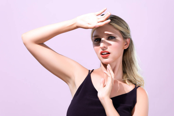 Closeup young blond hair woman with perfect skin and soft alluring facial makeup raise her hand cover her face from bright sunlight in pink isolated background for skincare sunscreen product. - Foto, Bild