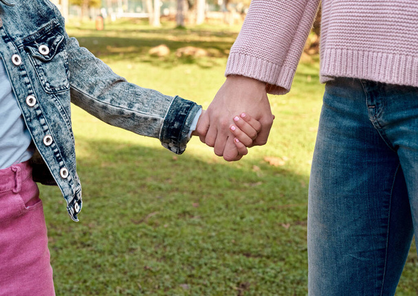 If you love them, keep them safe. a little girl holding her mothers hand while going for a walk in the park - Foto, imagen