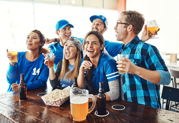 Verzamel de jongens voor de grote wedstrijd. een groep vrienden die een biertje drinken tijdens het kijken naar een sportwedstrijd in een bar - Foto, afbeelding